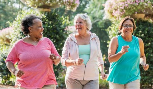 3 ladies engaging in a a brisk walk on a sunny day with smiles